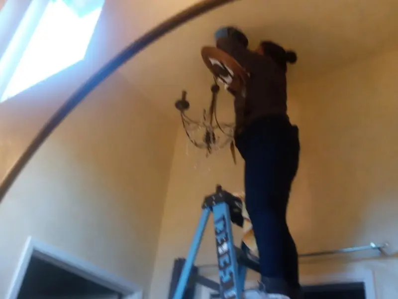 Electrician installing a chandelier in a L'Anse residence